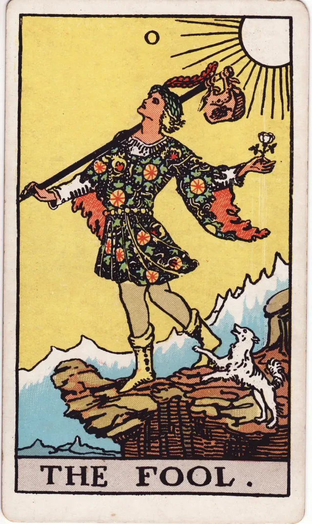 A carta O Louco, do tarô Rider-Waite-Smith: um andarilho à beira de um penhasco, com um cachorro aos pés.