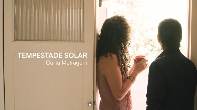 Quadro de abertura do curta Tempestade Solar: uma mulher de cabelo cacheado, com uma caneca vermelha na mão, e um homem de costas olham juntos por uma porta aberta para um jardim claro; à esquerda, a porta de vidro canelado com o título em letras brancas.