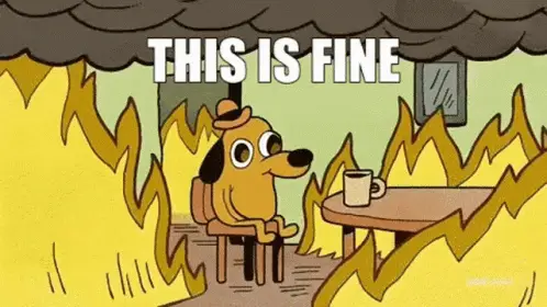 Um cachorro de chapéu sentado à mesa, com uma caneca de café, numa sala em chamas; no alto, o letreiro THIS IS FINE.