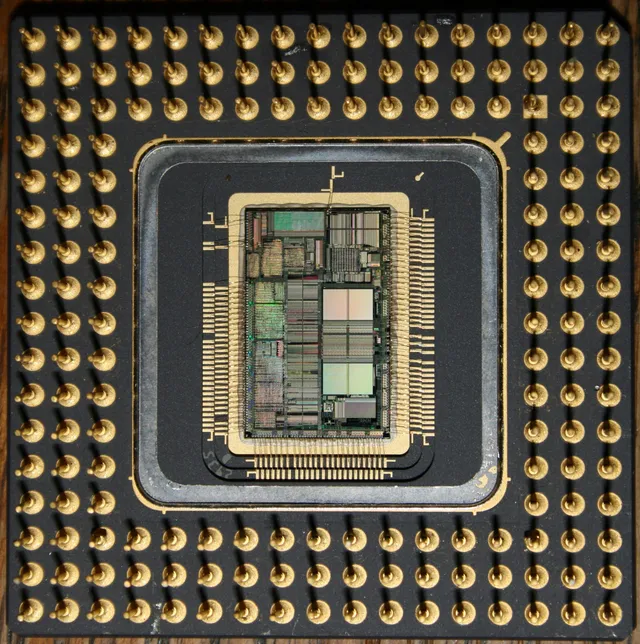 Um Intel 80486 aberto, o die à vista entre os pinos dourados: o programa virando silício